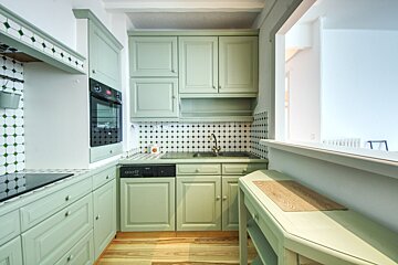 A kitchen with green cabinets and a black stove top oven