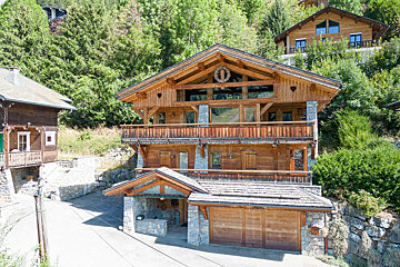 A large wooden house with a circular decoration on the roof