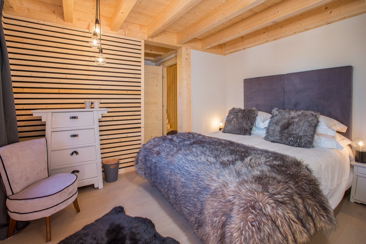 A bedroom with a bed a chair and a dresser