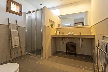 A bathroom with two sinks and a walk in shower