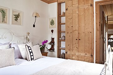 A bedroom with a white bed and wooden cabinets