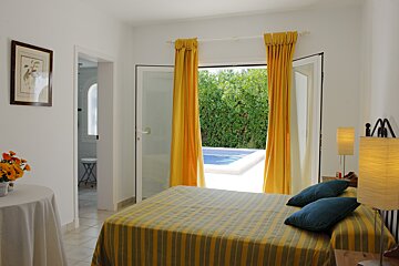A bedroom with a striped bed and yellow curtains