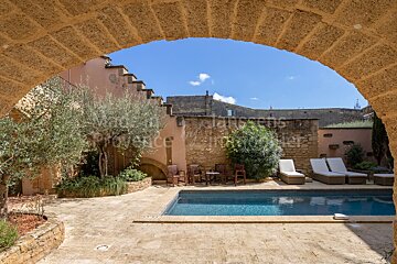 A swimming pool is surrounded by chairs and a stone wall with the word provence on it