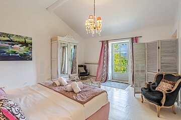 A bedroom with a painting on the wall above the bed