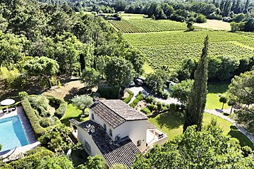 An aerial view of a house surrounded by trees and vineyards