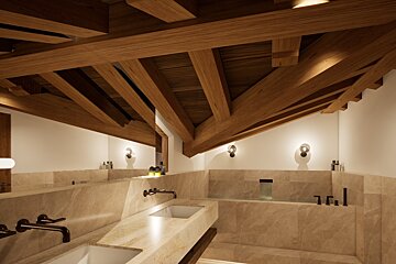 A bathroom with two sinks and a bathtub under a wooden ceiling