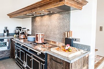 A kitchen with pots and pans on the stove and a cutting board on the counter