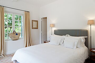 A bedroom with a bed and a basket on the window sill