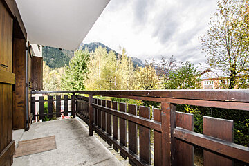 A balcony with a wooden fence and mountains in the background
