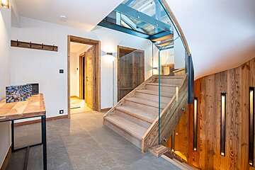 A wooden staircase with a glass railing in a hallway