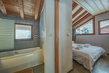 A bedroom with a bathtub and a large window