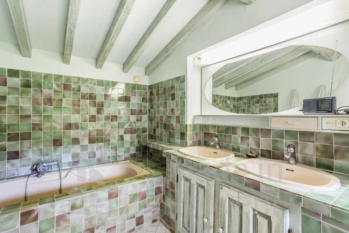 A bathroom with green tiles and two sinks