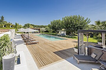 A large swimming pool is surrounded by chairs and umbrellas