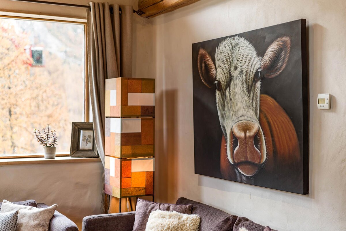 A painting of a cow is hanging on a wall in a living room
