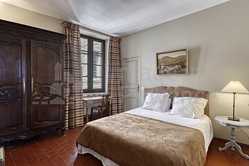 A bedroom with a painting on the wall above the bed