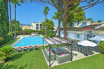 A large swimming pool is surrounded by lawn furniture and umbrellas