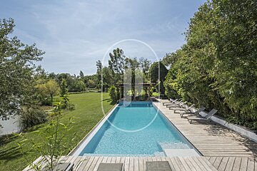 A large swimming pool is surrounded by chairs and trees
