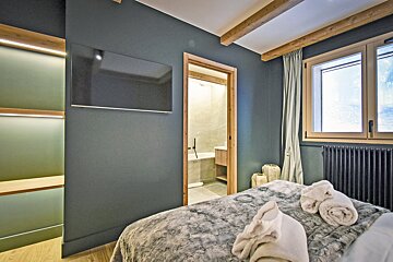A bedroom with a bed and a television above it