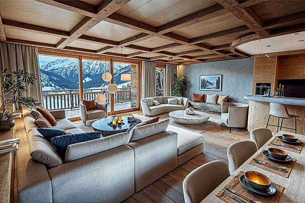 A luxurious chalet living room with stunning mountain views, featuring a cozy fireplace, wooden beam ceilings, plush seating, and a dining area.