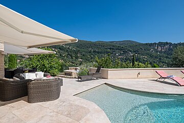 A patio with a swimming pool and mountains in the background