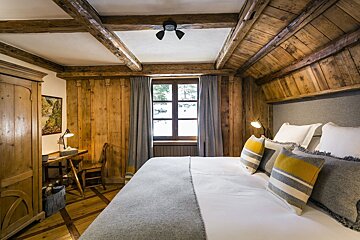 A bedroom with wood paneling and a large bed