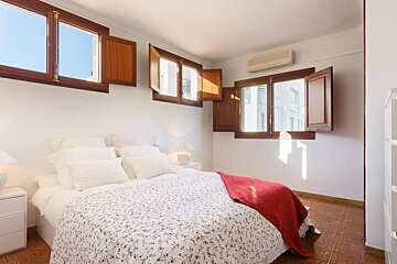 A bedroom with a bed and a window with shutters open
