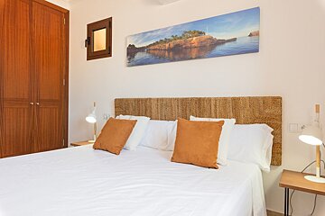 A bedroom with a painting on the wall above the bed