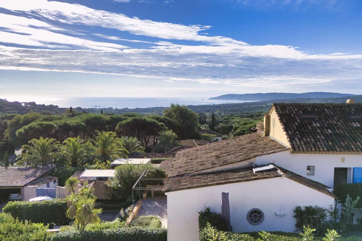 A white house with a tiled roof and a view of the ocean