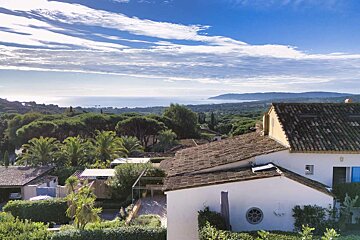 A white house with a tiled roof and a view of the ocean