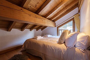 A bedroom with a wooden ceiling and a bed