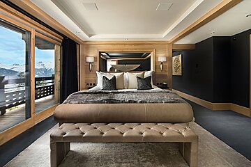 A bedroom with a large bed and a bench