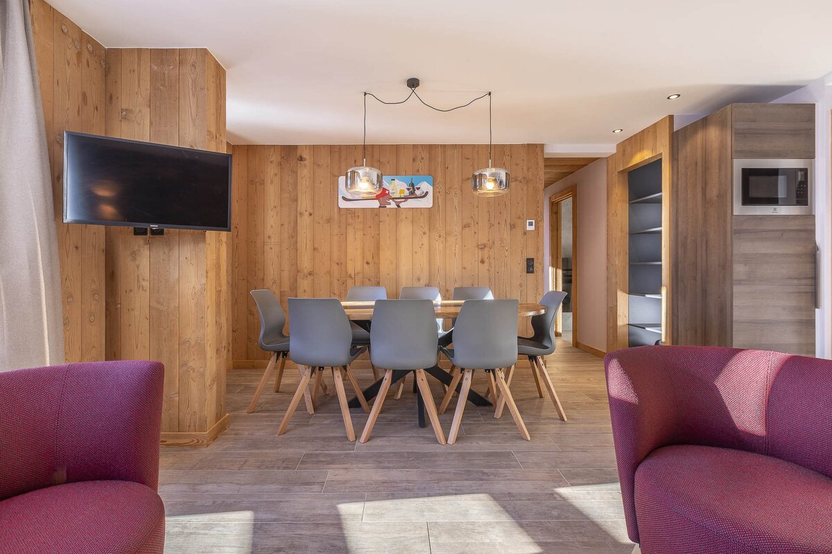 A dining room with a table and chairs and a flat screen tv