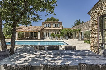 A large stone house with a swimming pool in front of it