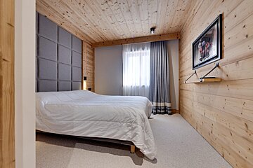 A bedroom with a bed and a television on the wall