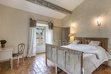 A bedroom with a bed and a window with the word maxim on the wall