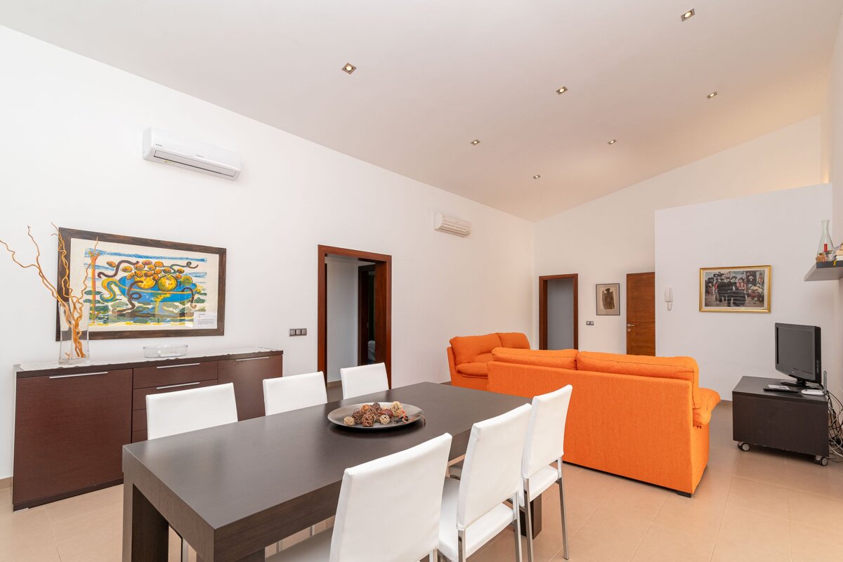 A living room with an orange couch and a dining table