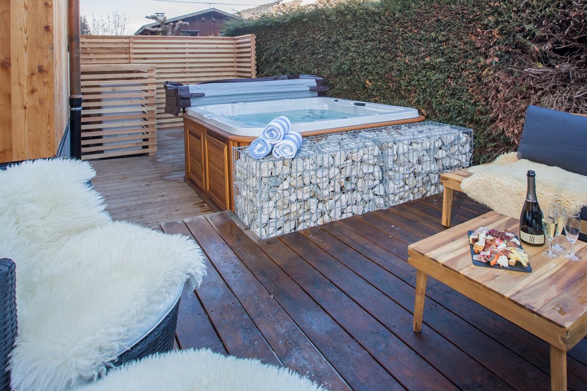 A bottle of champagne sits on a table next to a hot tub