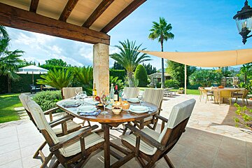 A patio with a table and chairs and a bottle of wine