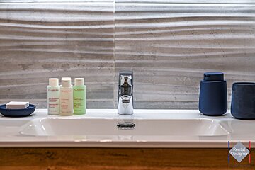 A bathroom sink with three bottles of clarins on it