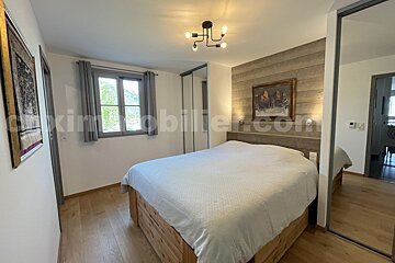 A bedroom with a large bed and a painting on the wall above it that says immobilier.com