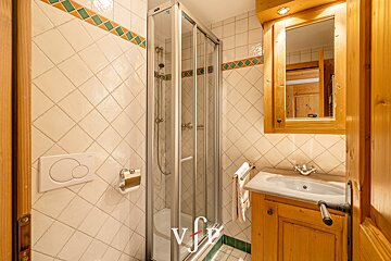 A bathroom with a sink and a shower with the letter v on it