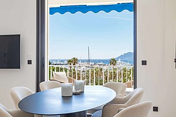 A dining room with a table and chairs and a view of the ocean