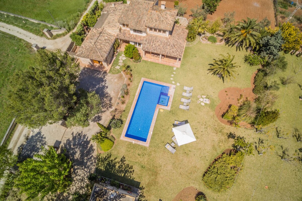 An aerial view of a large house with a large swimming pool