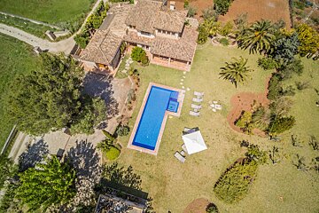 An aerial view of a large house with a large swimming pool
