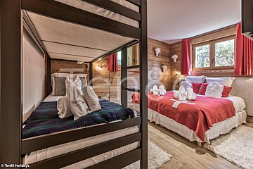 A bedroom with two bunk beds and a bed with a red blanket