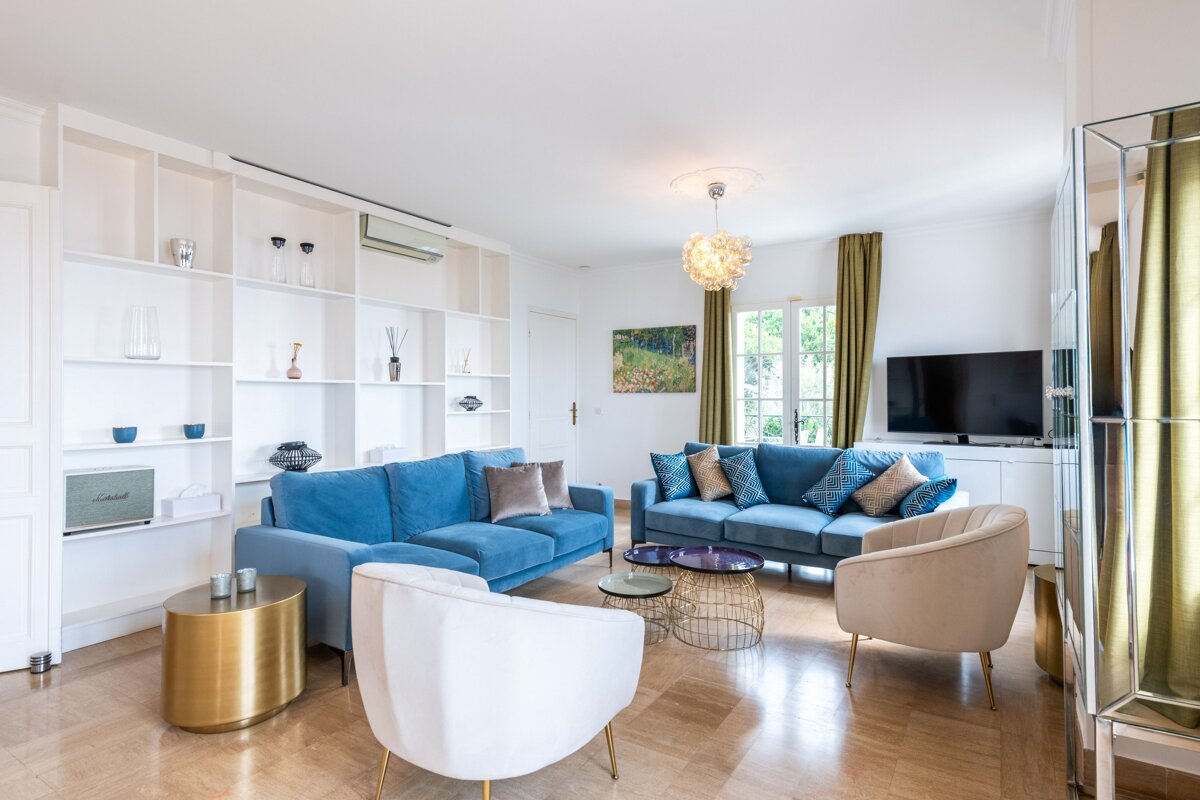 A living room with a blue couch and white chairs