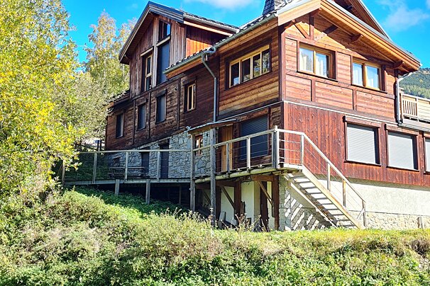 A large wooden house with stairs leading up to it
