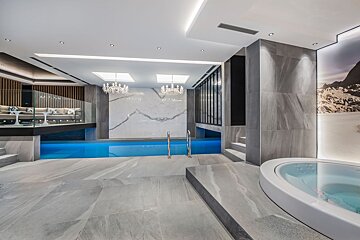 A large indoor swimming pool with a hot tub next to it