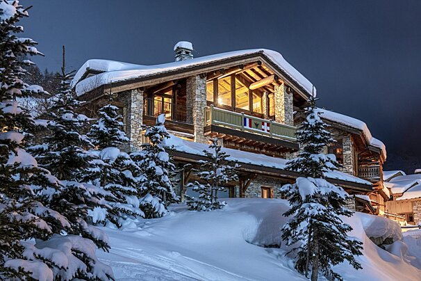 A snowy house with a swiss flag on the balcony