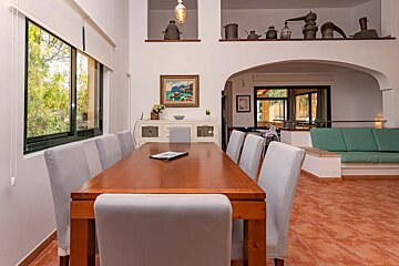 A dining room with a table and chairs and a painting on the wall